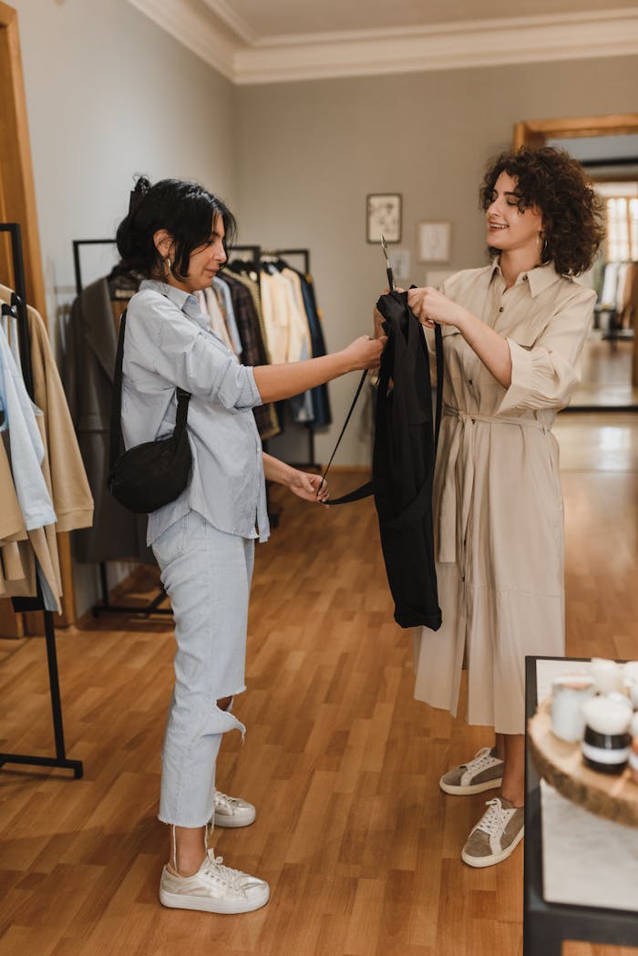 Women enjoying a shopping experience in a boutique, trying on clothes and smiling.